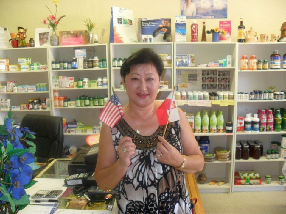 Tungalag in her Polish apothecary, holding the American and Polish flags