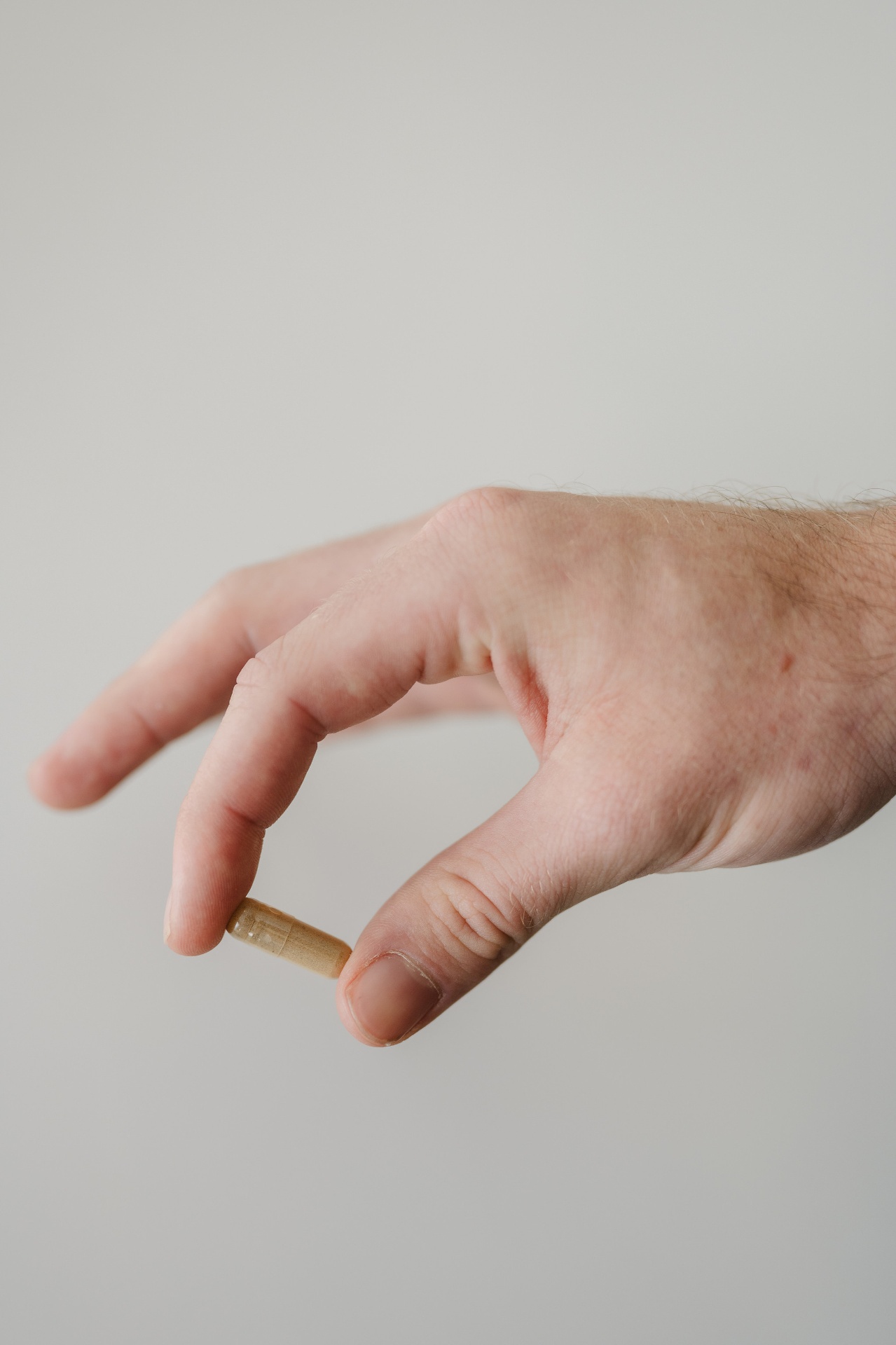 A hand gently holding a single Och Wellness herbal capsule
